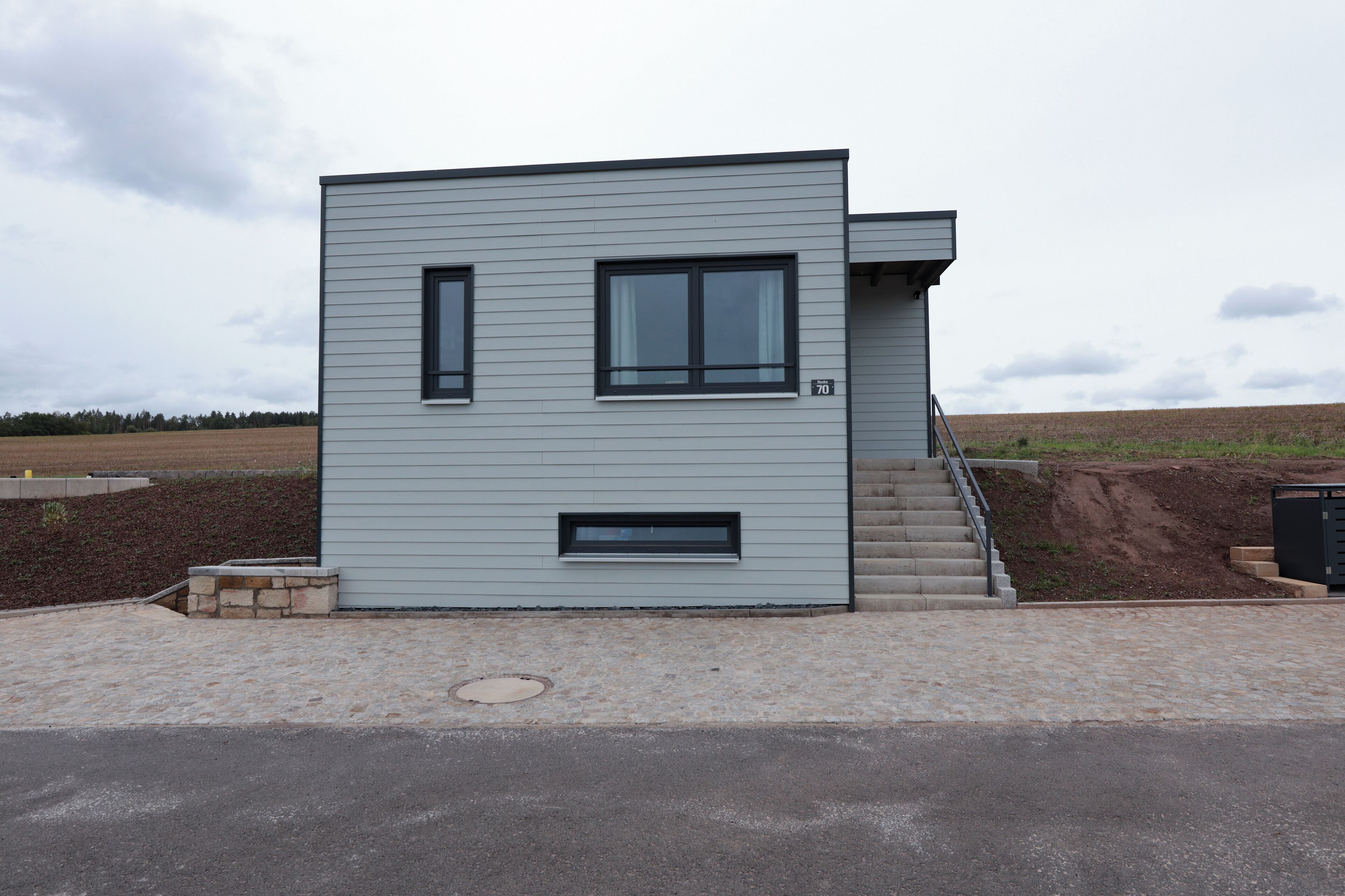 Een modern gebouw met twee verdiepingen, een plat dak en een kleine trap naar de bovenverdieping.