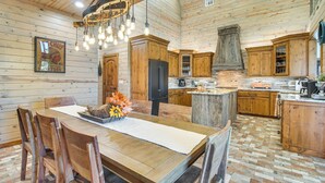 A spacious kitchen with wooden cabinets, a central island, and a hanging light fixture. - Upscale A-frame Escape w/ Lake Access in Quinton! (Eufaula)