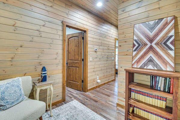 A wooden interior with a sofa, a small table, a bookshelf, and a door. - Upscale A-frame Escape w/ Eufaula Lake Access! (Eufaula)