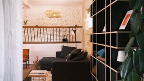 A modern living room with a black sofa, a wooden coffee table, and a white brick wall. - Maison Monsieur Léger Maison de vacances (Montaut)