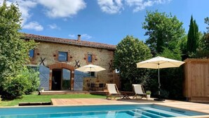 A stone building with a swimming pool, outdoor seating, and a wooden fence. - Maison Monsieur Léger Maison de vacances (Montaut)