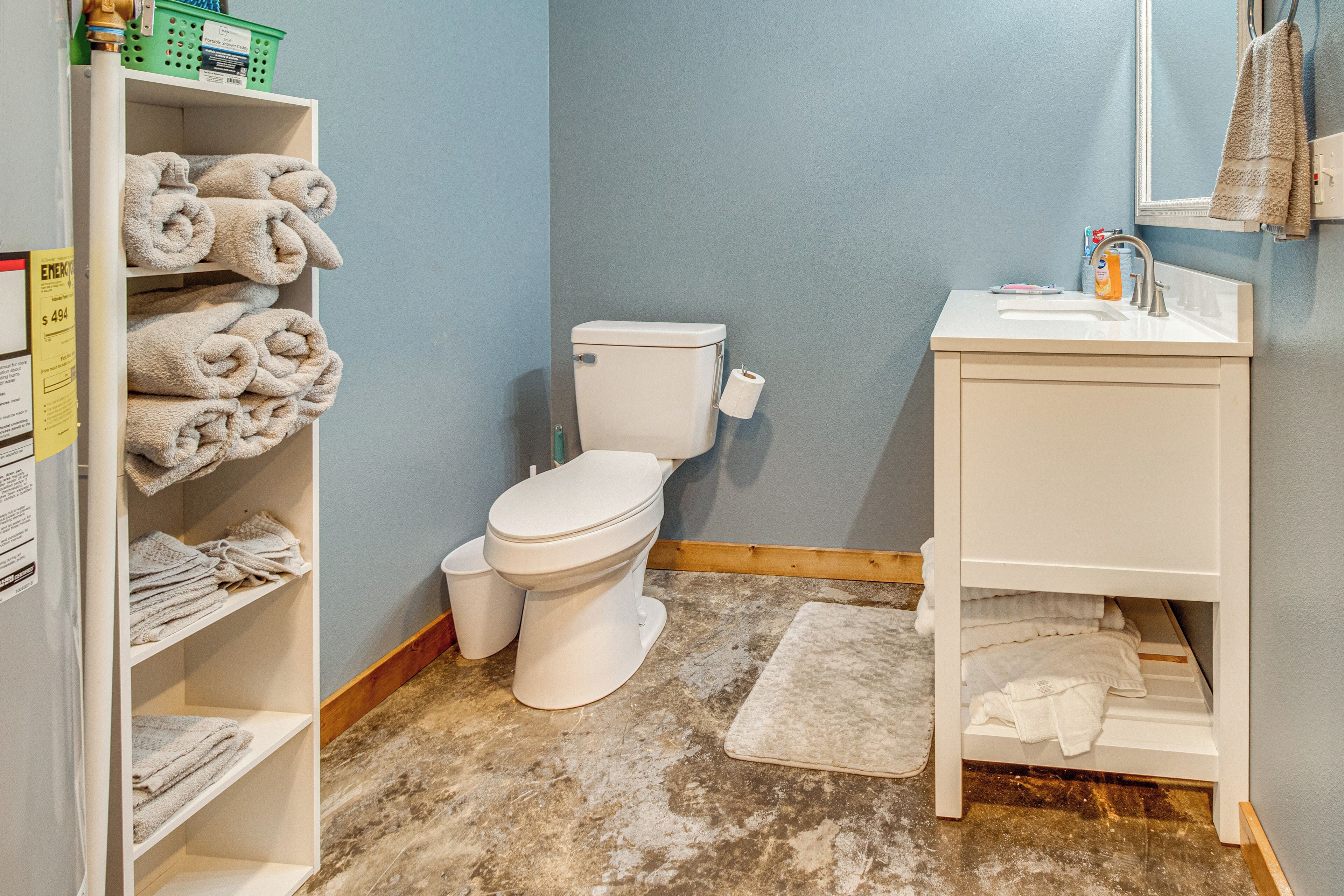 Een badkamer met toilet, wastafel en planken met handdoeken.