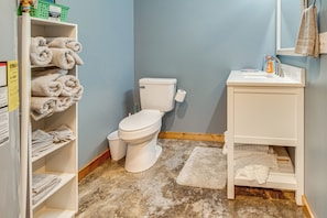Un bagno con il water, un lavandino e mensole con asciugamani.