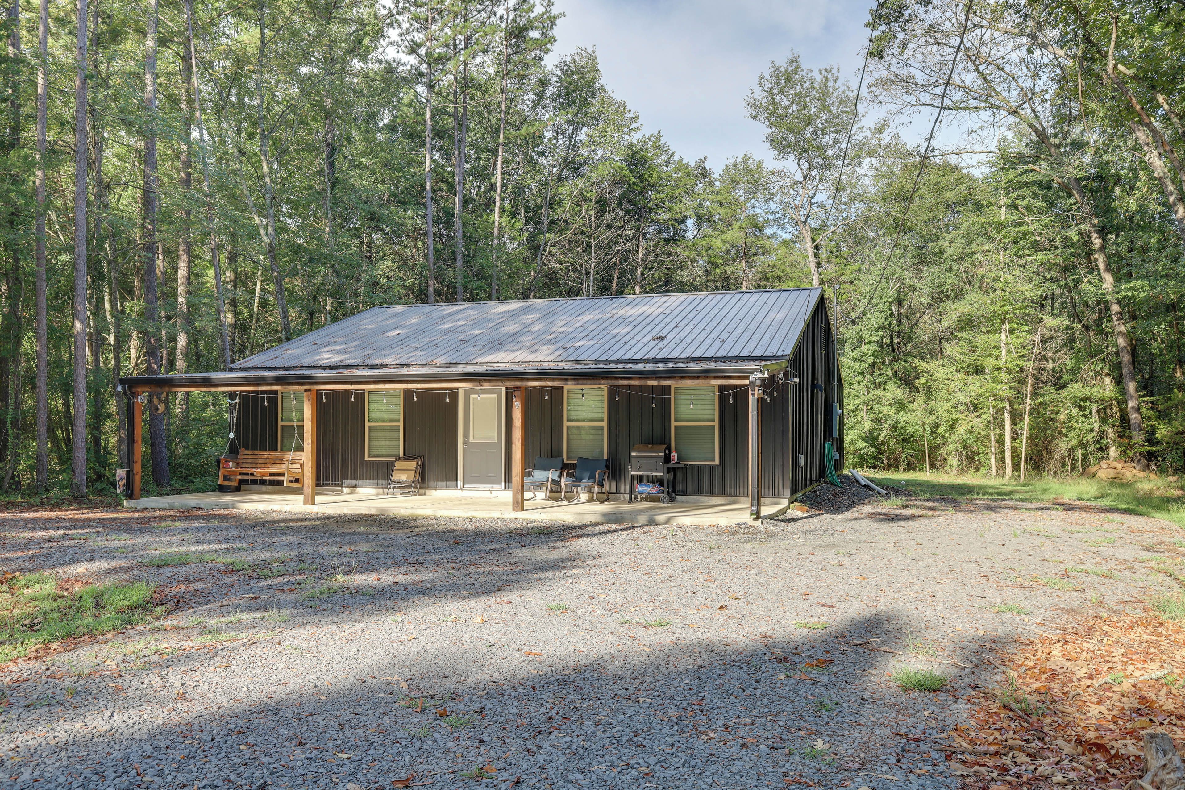 A cabin with a covered porch, a grill, and a bench.