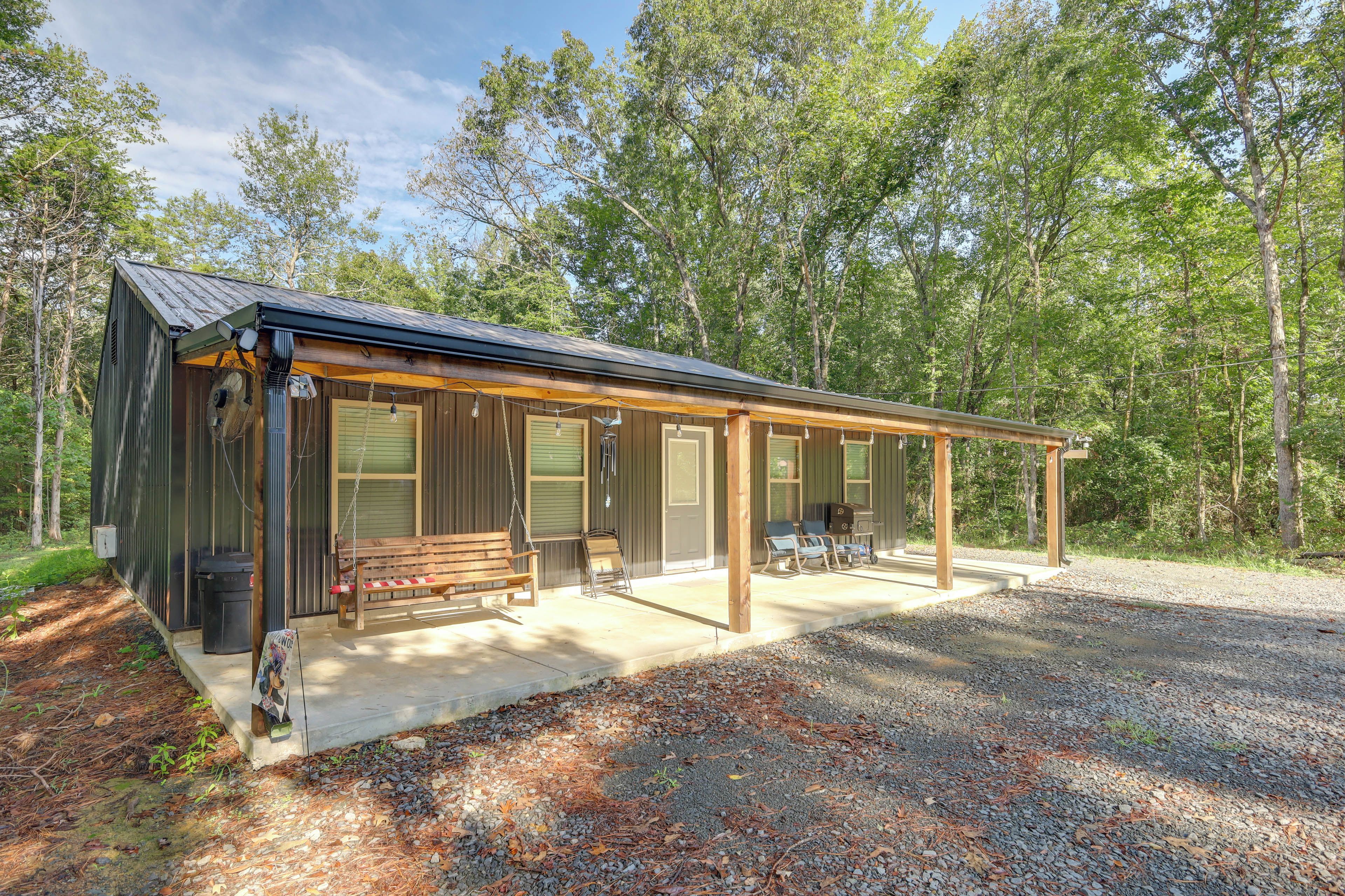 A cabin with a porch, a swing, and a grill.
