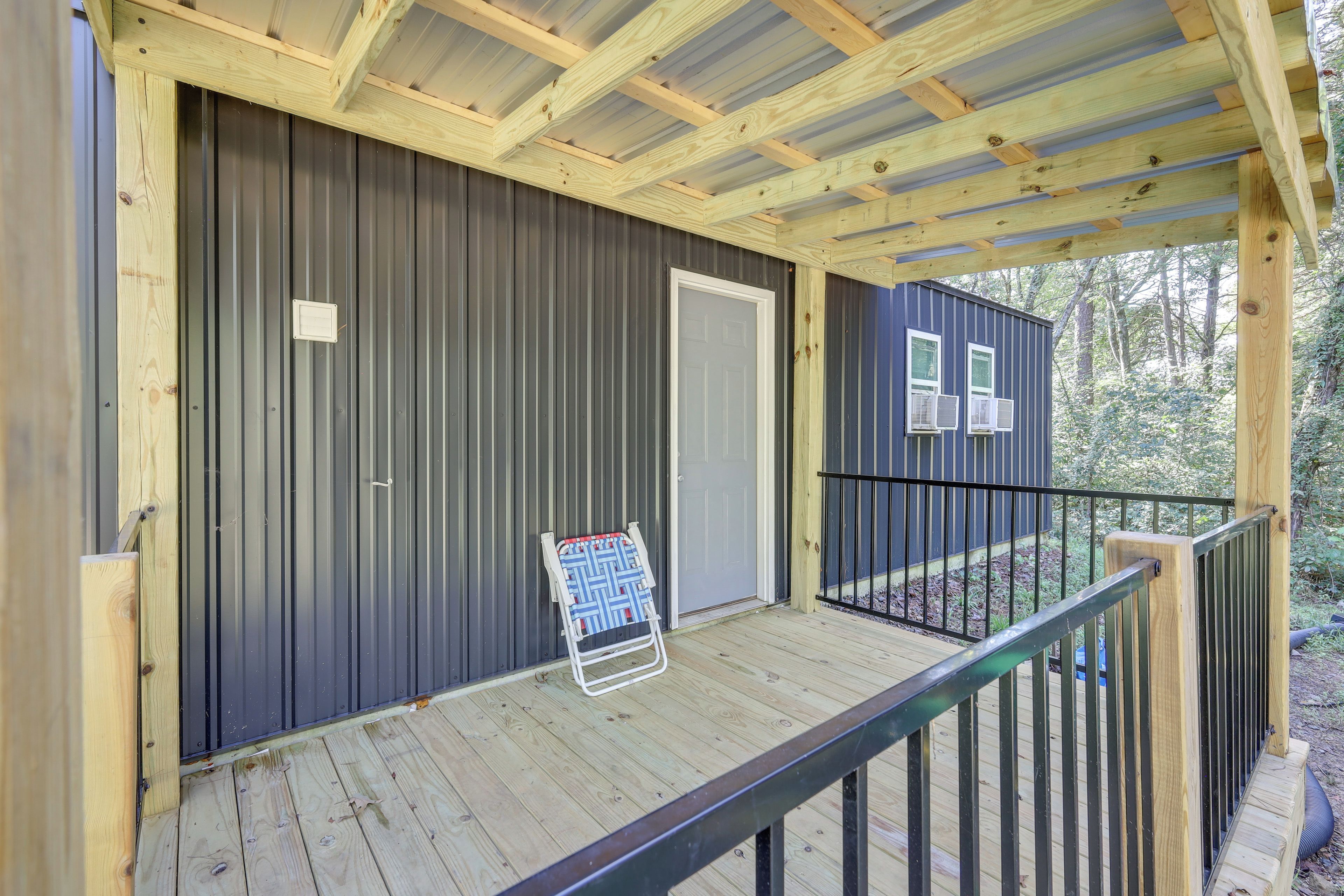 A covered porch with a metal door and a small sign.