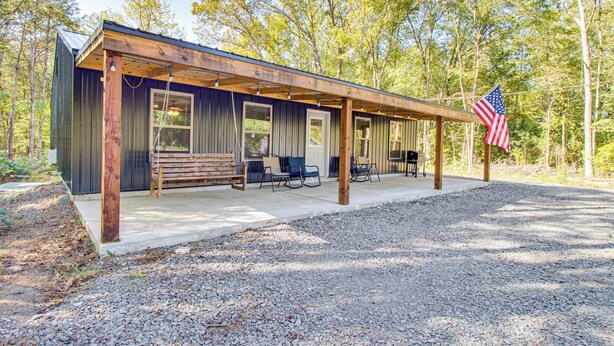 A cabin with a covered porch, a flag, and a gravel driveway. - 1 Mi to Greers Ferry Lake! Outdoor Adventure Base (Higden)