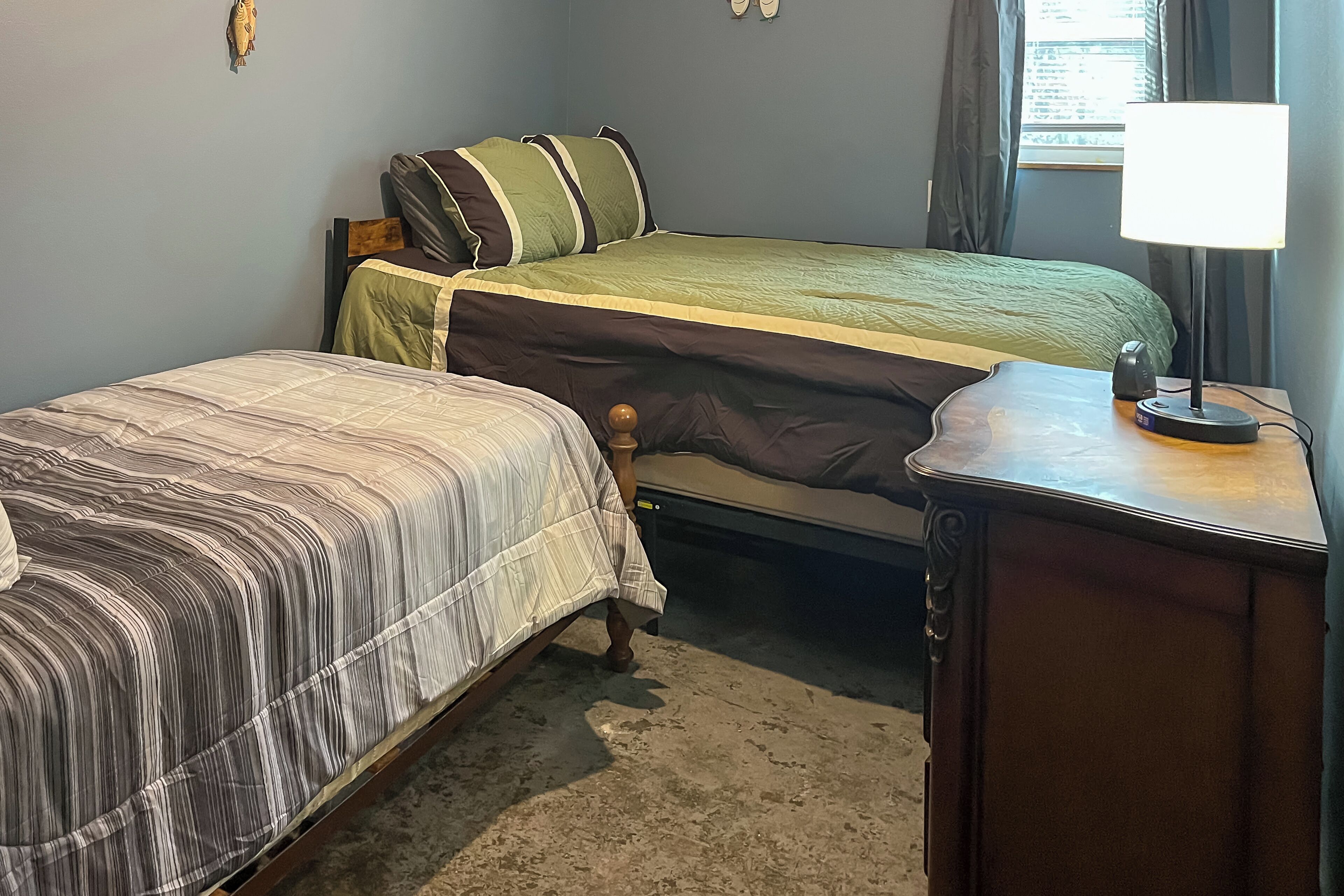 A bedroom with two beds, a nightstand, and a lamp.