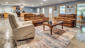 A spacious living room with a large brown sectional sofa, a beige leather chair, and a wooden coffee table. - 1 Mi to Greers Ferry Lake! Outdoor Adventure Base (Higden)
