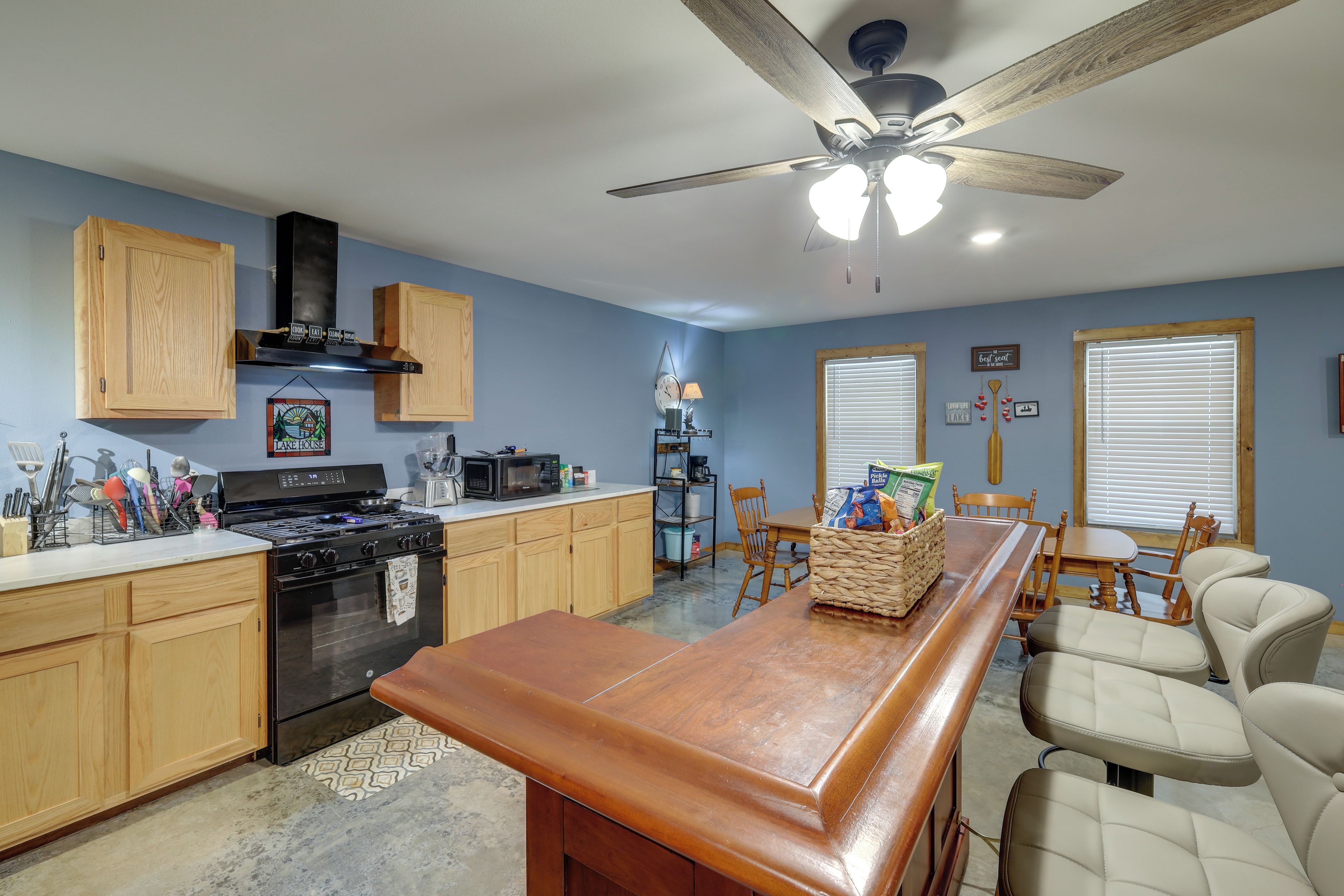 A kitchen with wooden cabinets, a stove, and a ceiling fan.