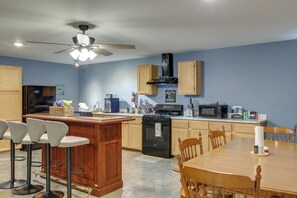 A modern kitchen with a central island, wooden cabinets, a black stove, and a ceiling fan. - 1 Mile to the Water, Boat & RV Hookup, Pets Ok! (Higden)