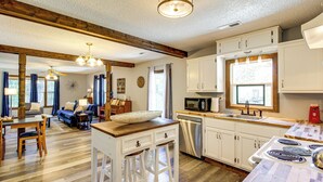 A spacious kitchen with white cabinets, a wooden dining table, and a bar area.
