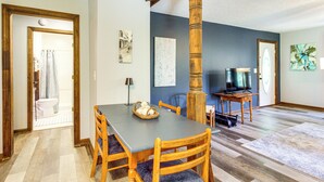 A dining area with a wooden table and chairs, a television, and artwork on the walls.