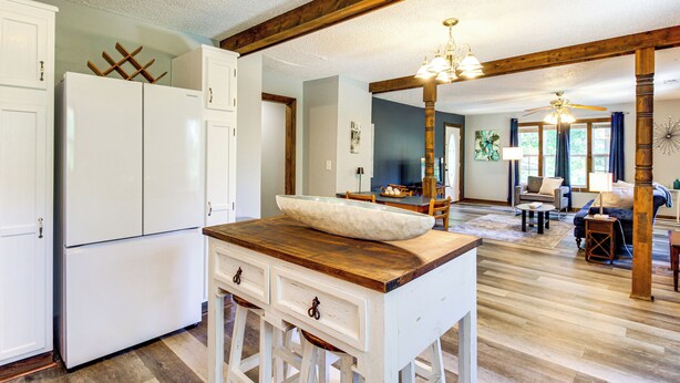 A spacious kitchen with white cabinetry, a wooden countertop, and a large white bowl.