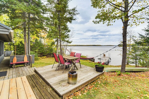 A wooden deck with a table and chairs, overlooking a lake. - Private Peninsula! Modern-rustic Fall Lake Cabin (Ely)