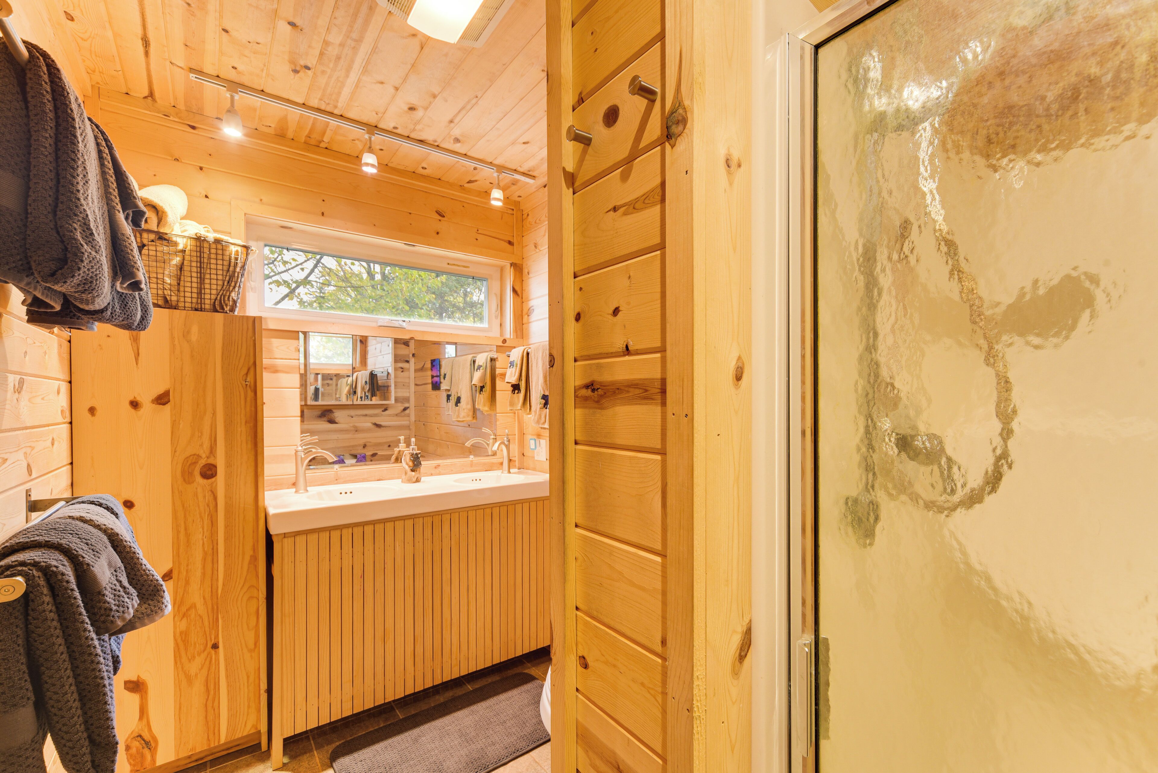 L’intérieur d’une cabane en bois, avec un plancher en bois, une fenêtre, un évier et une porte.