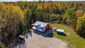 A red house with a blue roof surrounded by a forest.