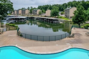 Une piscine avec un quai et des bateaux, entourée d’une zone abritée où se trouvent des chaises longues.