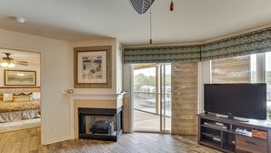 A living room with a fireplace, a television on a stand, and a balcony with a view. - Waterfront Balcony! Condo on Lake of the Ozarks (Lake Ozark)