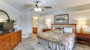 A bedroom with a bed, a dresser, a television, a ceiling fan, and two bedside lamps. - Waterfront Balcony! Condo on Lake of the Ozarks (Lake Ozark)