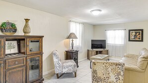 A living room with a sofa, a leopard print chair, a wooden cabinet, a television, and a lamp. - Jmagramo Listing Build Status Details Complete (Ormond Beach)