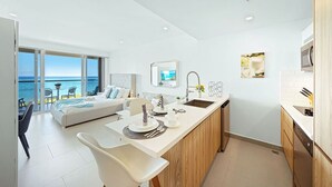 Een moderne keuken met een centraal eiland, een eethoek met uitzicht op zee, en een zithoek met een bank en een tafel.