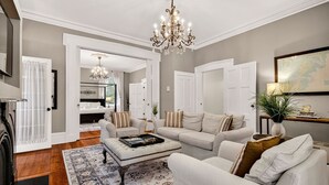 A spacious living room with a chandelier, a fireplace, and a large window. - Southern Charm + Timeless Elegance on Iconic Jones Street By Lucky Savannah (Savannah)