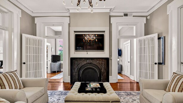 A spacious living room with a fireplace, two sofas, a coffee table, and a chandelier. - Southern Charm + Timeless Elegance on Iconic Jones Street By Lucky Savannah (Savannah)