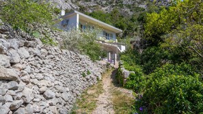 A stone wall, a pathway, and a building with a balcony.