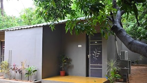 A small, single-story building with a grey exterior and a yellow entrance. - Whispering Rocks Jungle Resort (Gangavathi)