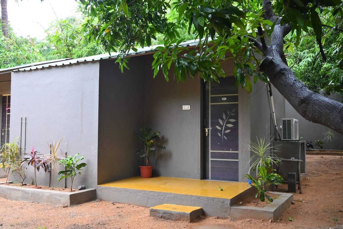 A small, single-story building with a grey exterior and a yellow entrance.
