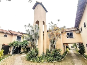 A courtyard with a central tower, surrounded by buildings with tiled roofs and windows.