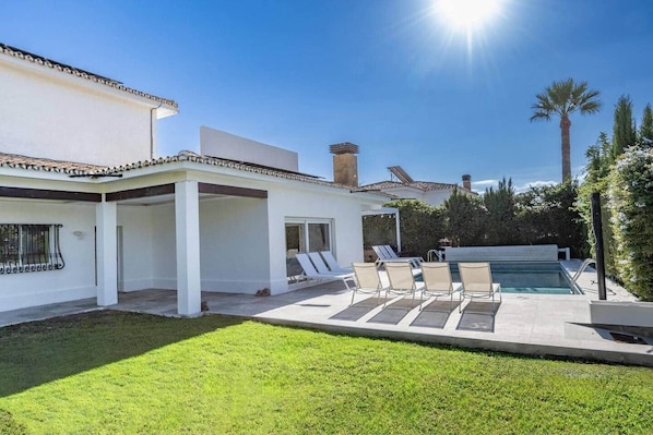 A modern house with a pool, outdoor seating, and a well-maintained lawn.
