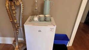 A compact white refrigerator with a small freezer section, a blue trash bin, and a decorative mirror with a gold frame. - Ru U Art (Richmond Hill)