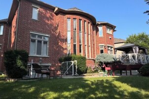 Un edificio de ladrillo rojo con fachada curva, un área de estar cubierta al aire libre y un pequeño jardín.