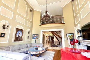 A spacious living room with a high ceiling, a staircase leading to an upper level, and a fireplace. - Ru U Art (Richmond Hill)