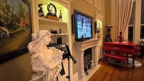 A living room with a fireplace, a television, a red piano, and a statue. - Ru U Art (Richmond Hill)