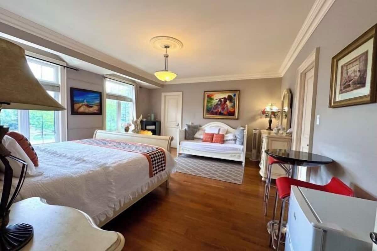 Quarto de hotel com duas camas, uma escrivaninha, uma cadeira, um abajur e obras de arte nas paredes.