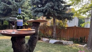A tree trunk with a tray holding a bottle of wine, a glass, and a plate of food. - Ru U Art (Richmond Hill)