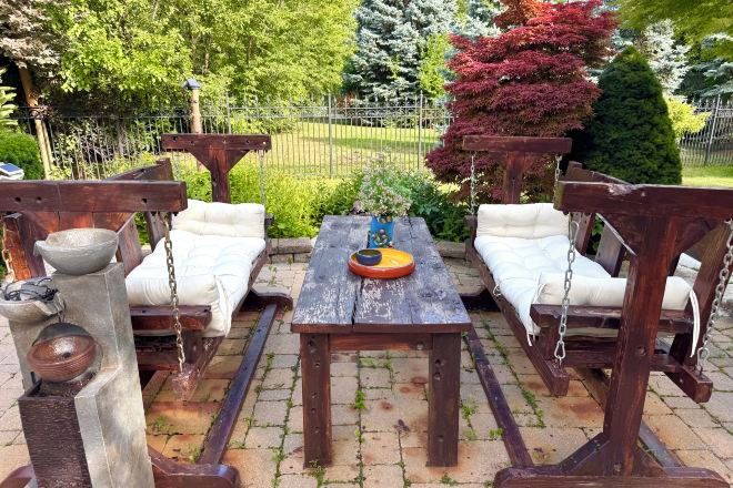An outdoor seating area with a wooden table and two swings.