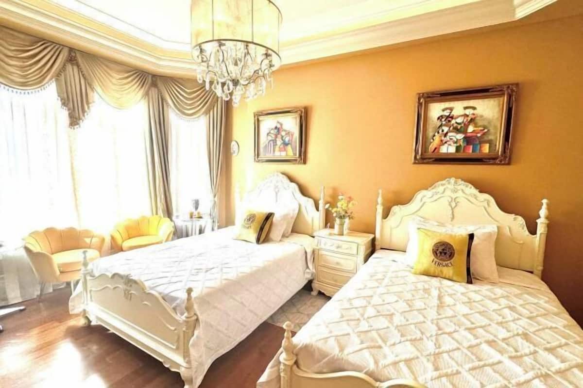Quarto de hotel com duas camas, um candelabro e obras de arte nas paredes.