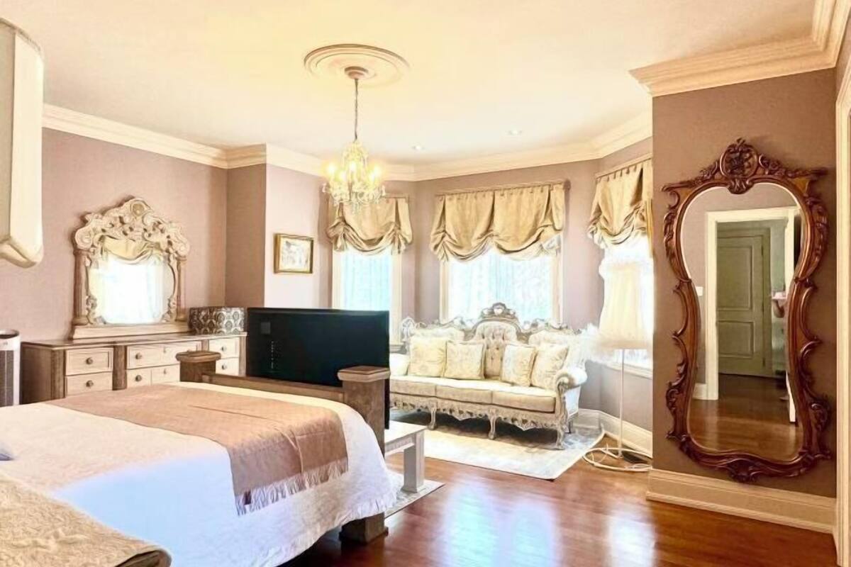 Quarto com cama grande, televisão, sofá e espelho.