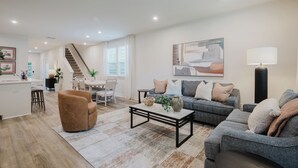 Ein modernes Wohnzimmer mit einer Couch, einem Couchtisch und einer Treppe, die in einen anderen Raum führt.