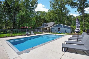 A swimming pool with lounge chairs, a house in the background, and a fenced garden area. - Union Pier home w/Heated pool fire pit screened porch large yard (Union Pier)