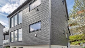 A modern two-story house with a wooden deck and a small garden area.