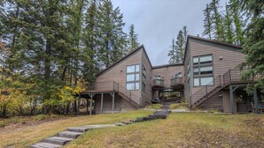 A two-story building with a covered porch and a staircase leading to the entrance. - Sans Souci 1, 3 Bedroom Ski In, Ski Out Retreat (Whitefish)