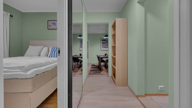 A bedroom with a bed, a desk, and a chair in the adjacent room.