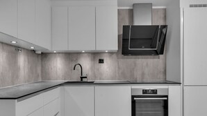 A modern kitchen with a built-in oven, a sink, and a range hood.