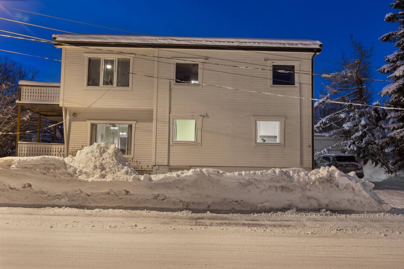 Una casa de dos pisos con un porche y un gran montículo de nieve en la parte delantera.