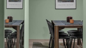 A dining area with a table and chairs, framed artwork on the wall, and pendant lighting.